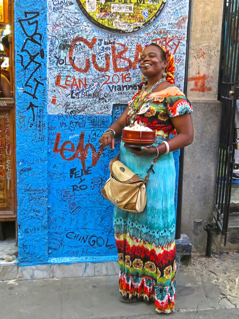 Afro-Cuban Culture Guide. Afro-Cuban woman fortune teller with a cigar in a colorful dress