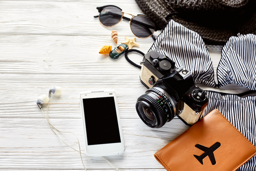 Essential travel documents, hat, sunglasses, camera, cell phone, passport and shells. Belize travel essentials. 