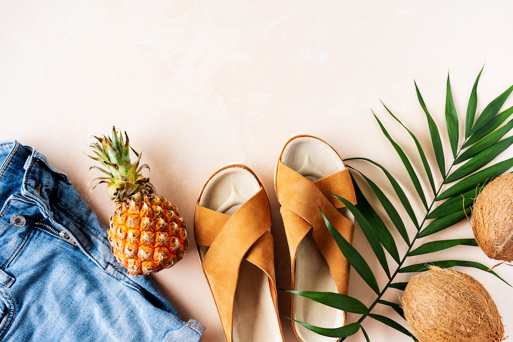 Trendy summer sandals, denim jean shorts, leather crisscross sandals on pink pastel background.  Belize travel essentials. 