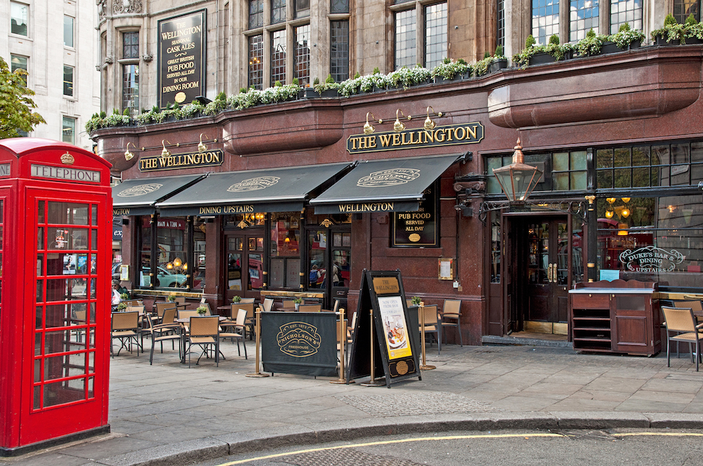 Image of typical pub in London, England with red phone booth. 