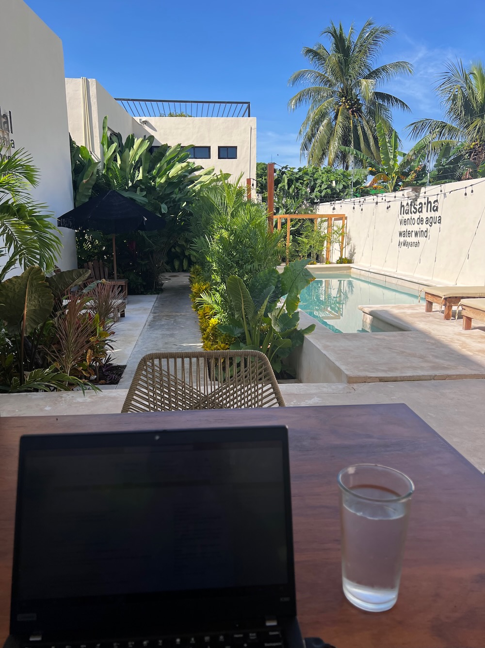 Laptop and glass of water in front of pool in at the Mayanah in Bacalar Lagoon, Mexico. 