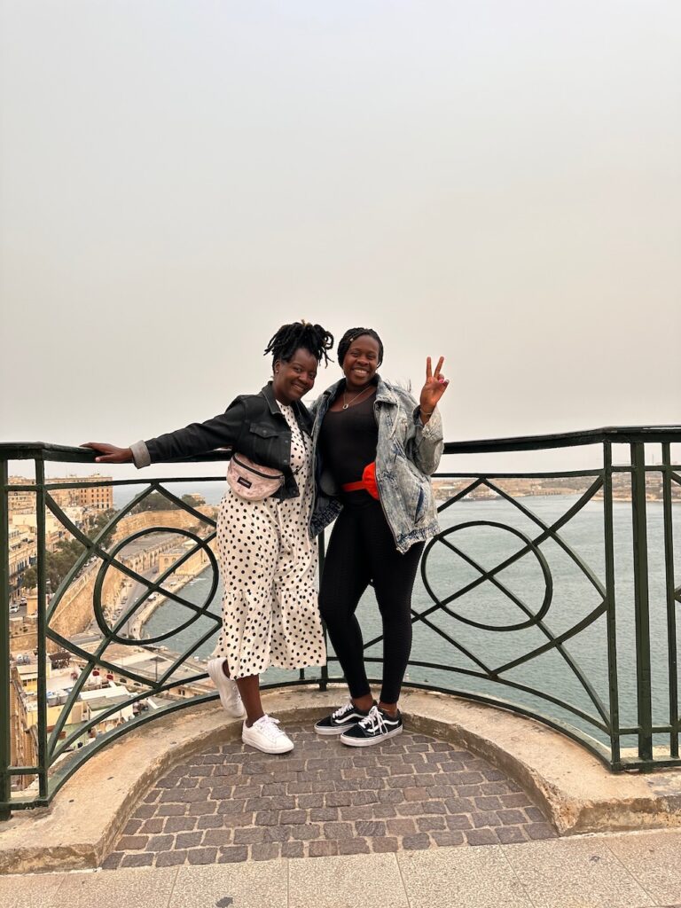 Two beautiful Black women in Upper Barrakka Gardens in Valetta, Malta posing overlooking bay. 