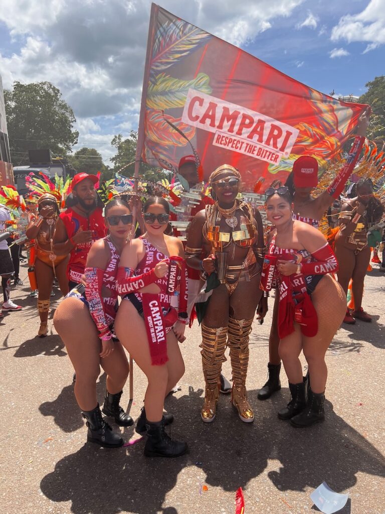 A group of woman dressed in Campari brand attire and Carnival Costume for Trinidad Carnival in Port of Spain, Trinidad.  How to plan for Trinidad Carnival 2024