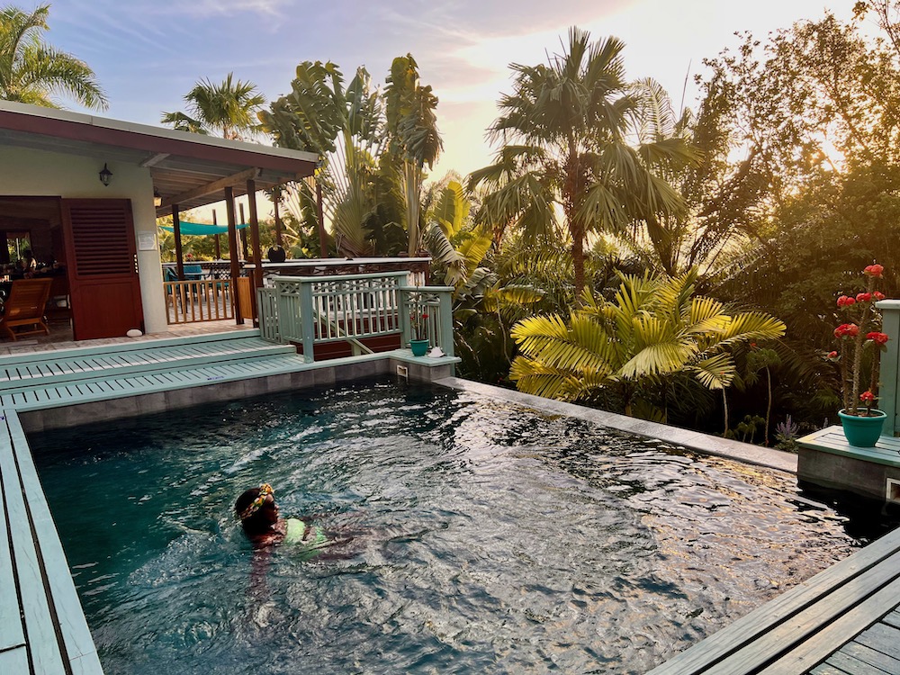 Black woman swimming in pool with lush trees in the background in Saint Lucia. How to maximize your vacation days in 2024. 