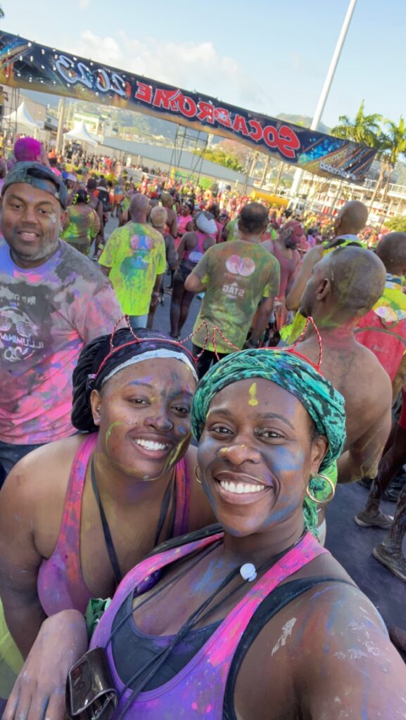 two black ladies with paint on their face with other people in the background.