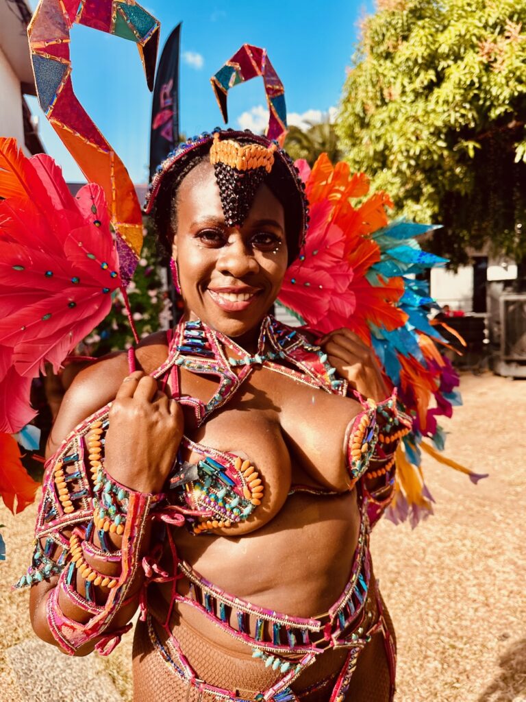 Black women at Trinidad Carnival 2024 dressed in colorful costume with elaborate sequins and feathers in Flamenco section with Tribe Carnival.