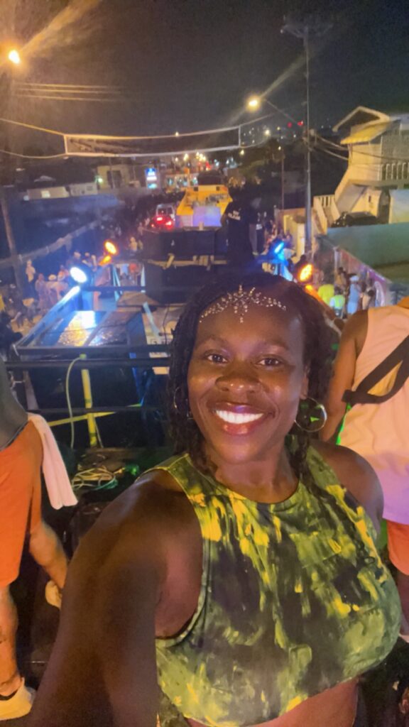 Black lady smiling wearing a green bathing suit with jewels on her face in Port of Spain, Trinidad. 