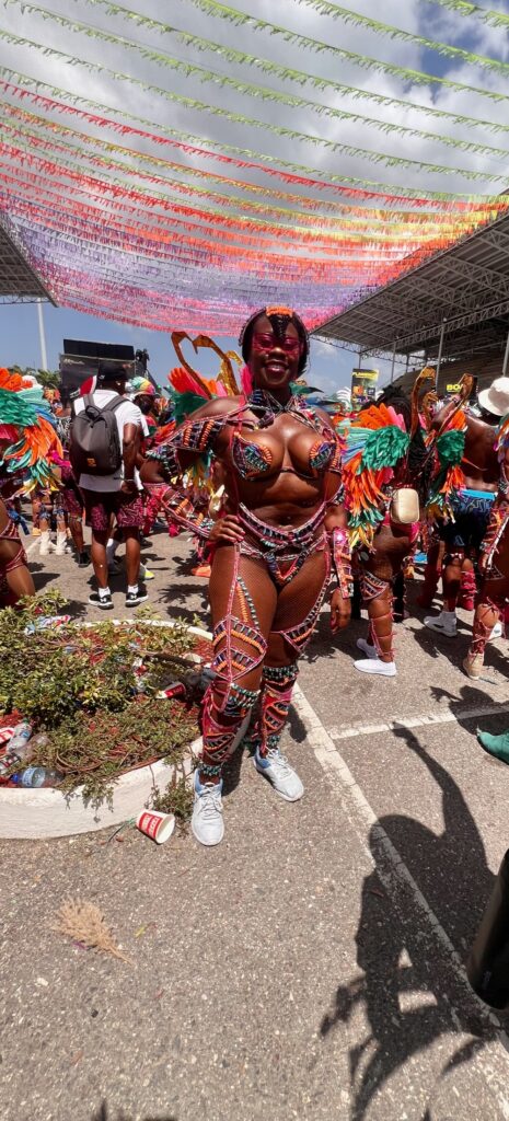 A Black Lady dressed in a vibrant costume with sneakers posing at the Socadrome waiting to cross the stage at Trinidad Carnival.