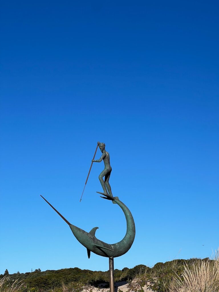 Fisherman statue standing on the tail or a swordfish with spear in hands 