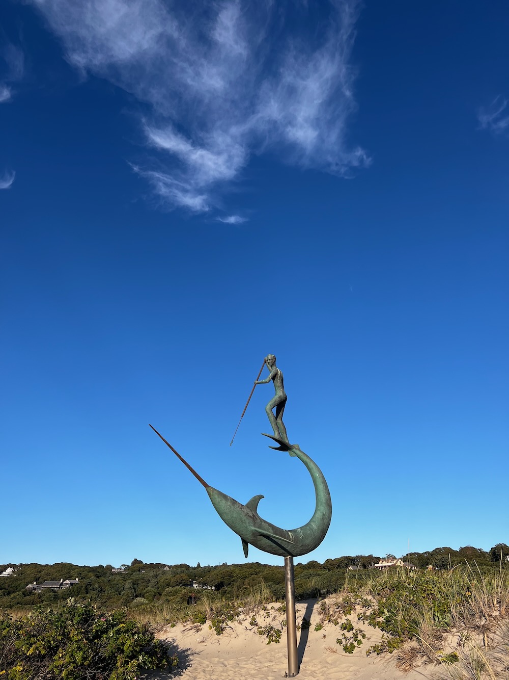 Statue of whaler standing on whales tail with spear. 