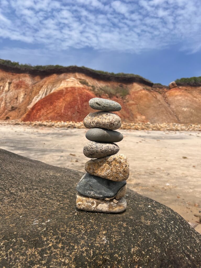 Rocks stacked up on a larger rock with the cliffs in the background in Aquinnah, Martha's Vineyard. 