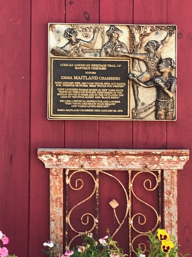 Gold plaque on mounted on the side of a red building.